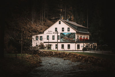 House amidst trees and buildings in city at night