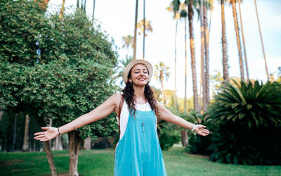 Portrait of smiling young woman standing against trees