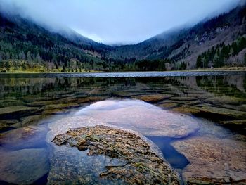 Scenic view of lake by mountains against sky