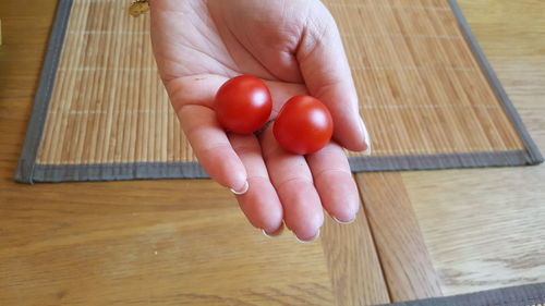 Midsection of person holding red chili on table