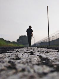 Side view of man standing on railroad track against sky