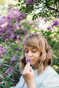 Candid authentic portrait of 30s 40s caucasian blonde woman with lilac flowers. 30 40 year old 