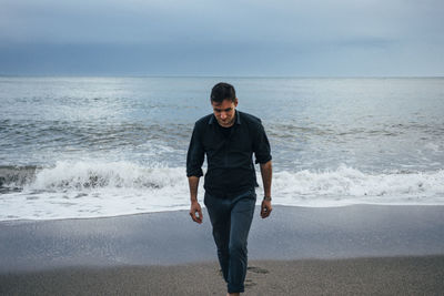 Full length of man standing on beach against sky