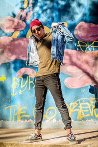 Portrait of young man standing against graffiti wall