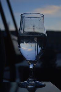 Close-up of wine glass on table against sky during sunset