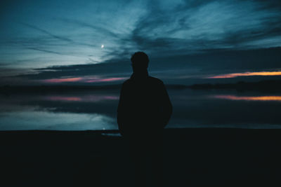 Silhouette woman standing by sea against sky during sunset