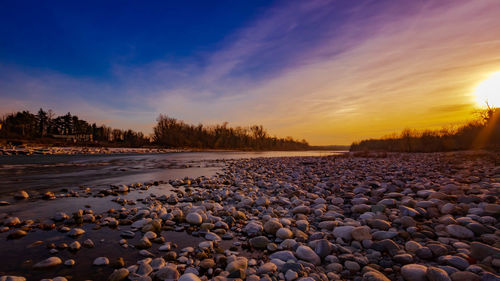 Surface level of stones on land against sky during sunset