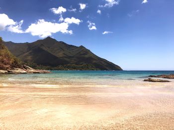 Scenic view of sea and mountains against blue sky