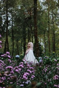 Side view of cheerful woman standing amidst plants