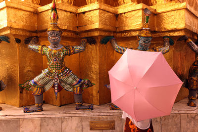 Person with umbrella by buddhist temple