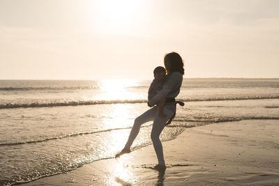 Mother carrying son while wading at beach