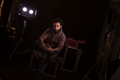 Portrait of man sitting in darkroom