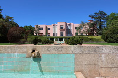 Woman standing by swimming pool against blue sky