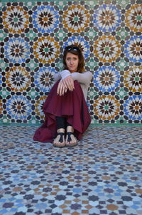 Portrait of young woman standing against multi colored flowers