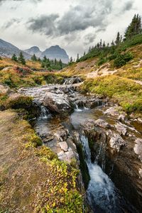 Scenic view of waterfall against sky in mountains during a hike