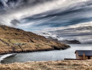 Scenic view of lake by snowcapped mountain against sky