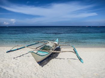 Deck chairs on beach against sky