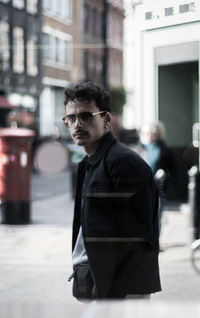 Portrait of young man standing in city