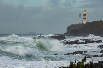 Lighthouse by sea against sky