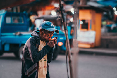 Man holding umbrella standing on street in city