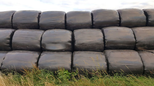 Stack of bales covered in black plastic on field