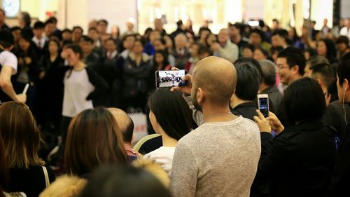 Rear view of man photographing performance