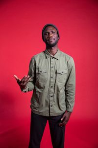 Portrait of young man standing against red background