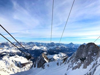 Overhead cable car over snowcapped mountains against sky