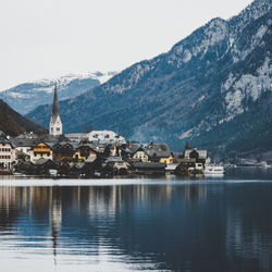 Houses by lake and mountains against clear sky