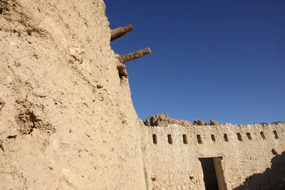 Low angle view of old ruins against clear blue sky at chebika