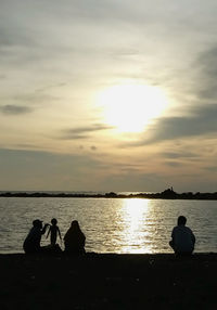 Silhouette of people in lake at sunset