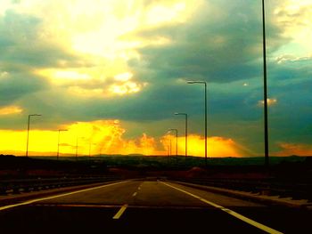 Scenic view of road against cloudy sky at sunset