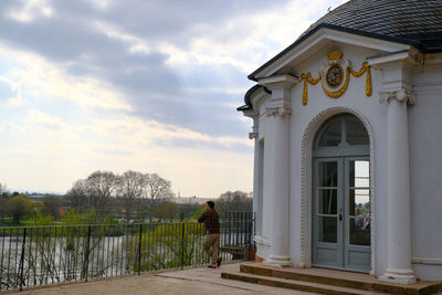 Rear view of man standing by building against sky