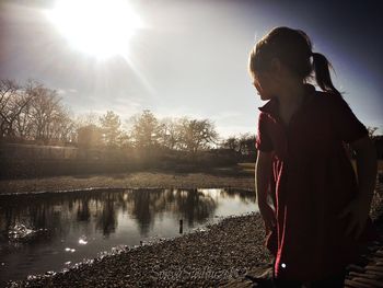 Girl standing at lakeshore on sunny day