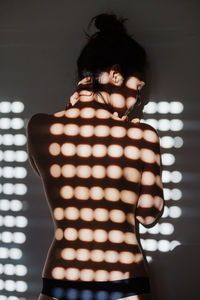 Rear view of woman standing against illuminated wall