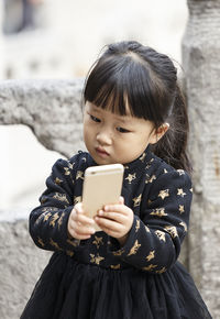 Portrait of girl holding smart phone during winter
