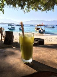 Close-up of drink on table at beach against sky