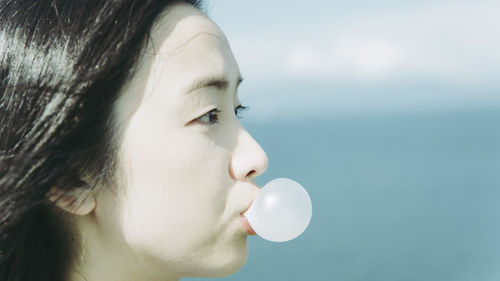 Close-up of beautiful woman blowing bubble gum