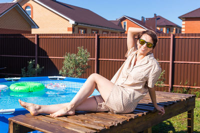 Portrait of woman sitting by swimming pool