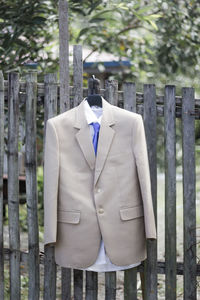Suit by wooden fence against trees