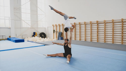 Instructor with teenage boy practicing gymnastics in club