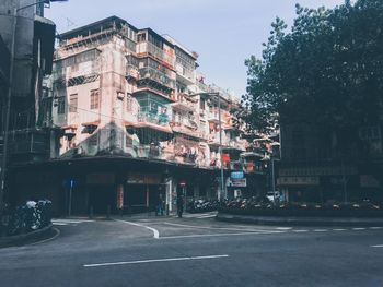 Road by buildings in city against sky