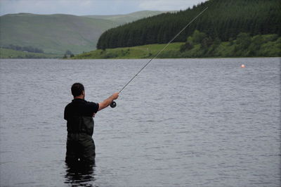 Rear view of man fishing in lake