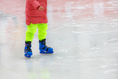 A teenager in bright clothes is skating in an ice stadium.