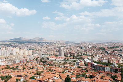 Aerial view of cityscape against cloudy sky