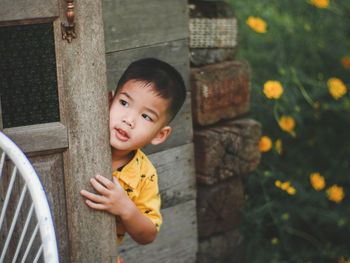 Cute boy standing behind wall