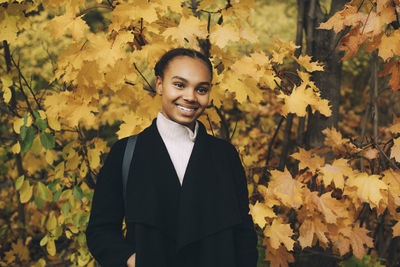 Portrait of smiling teenage girl standing against orange trees