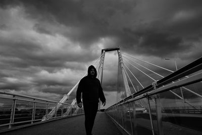 Rear view of man standing on footbridge against sky