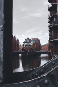 Bridge over river amidst buildings in city against sky