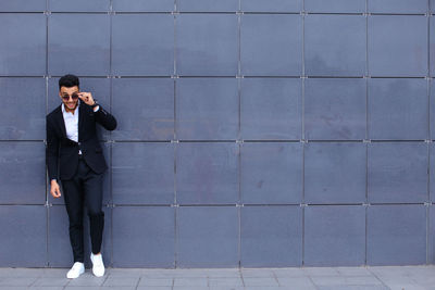 Full length of businessman standing against wall